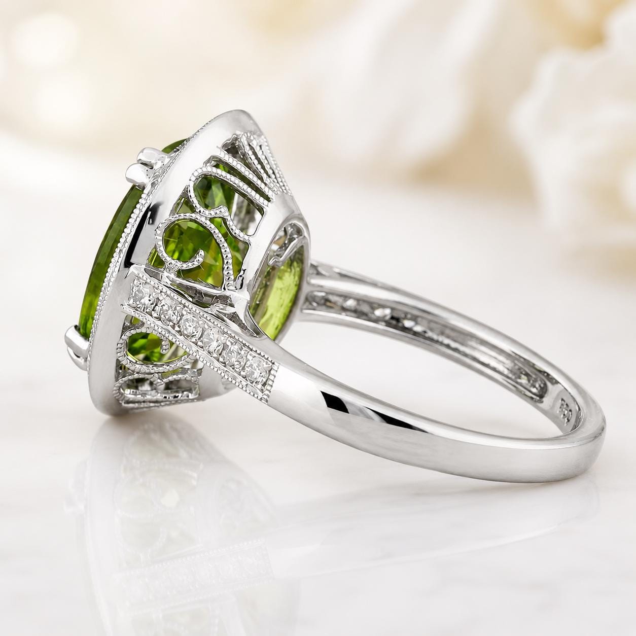 A silver ring with a large oval-shaped green gemstone, possibly a peridot, set in a decorative metal band.