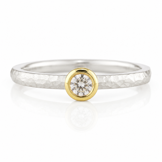 A silver ring with a large diamond set in the center, surrounded by a thin gold band.