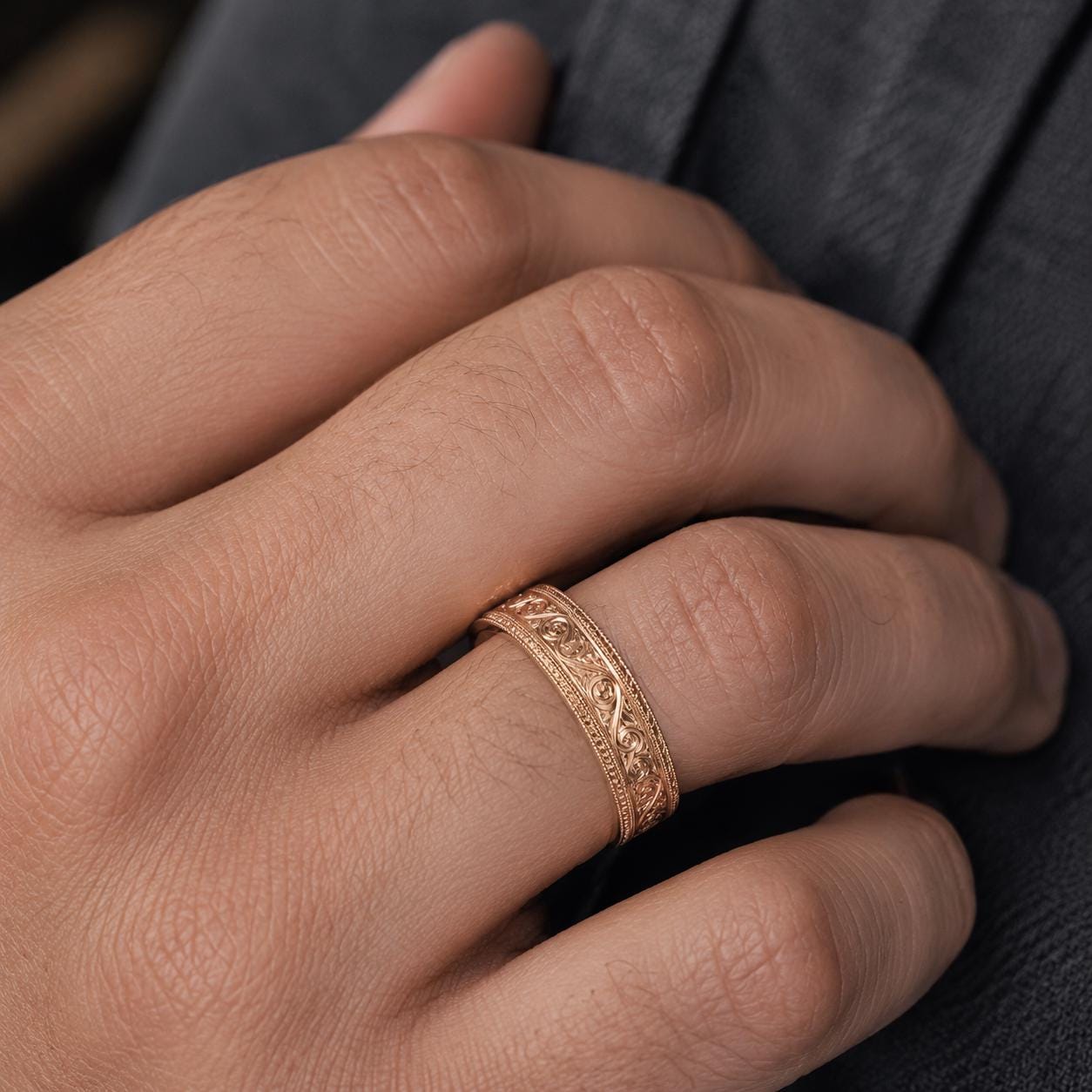 A close-up image of a person's hand wearing a gold ring with an intricate design.