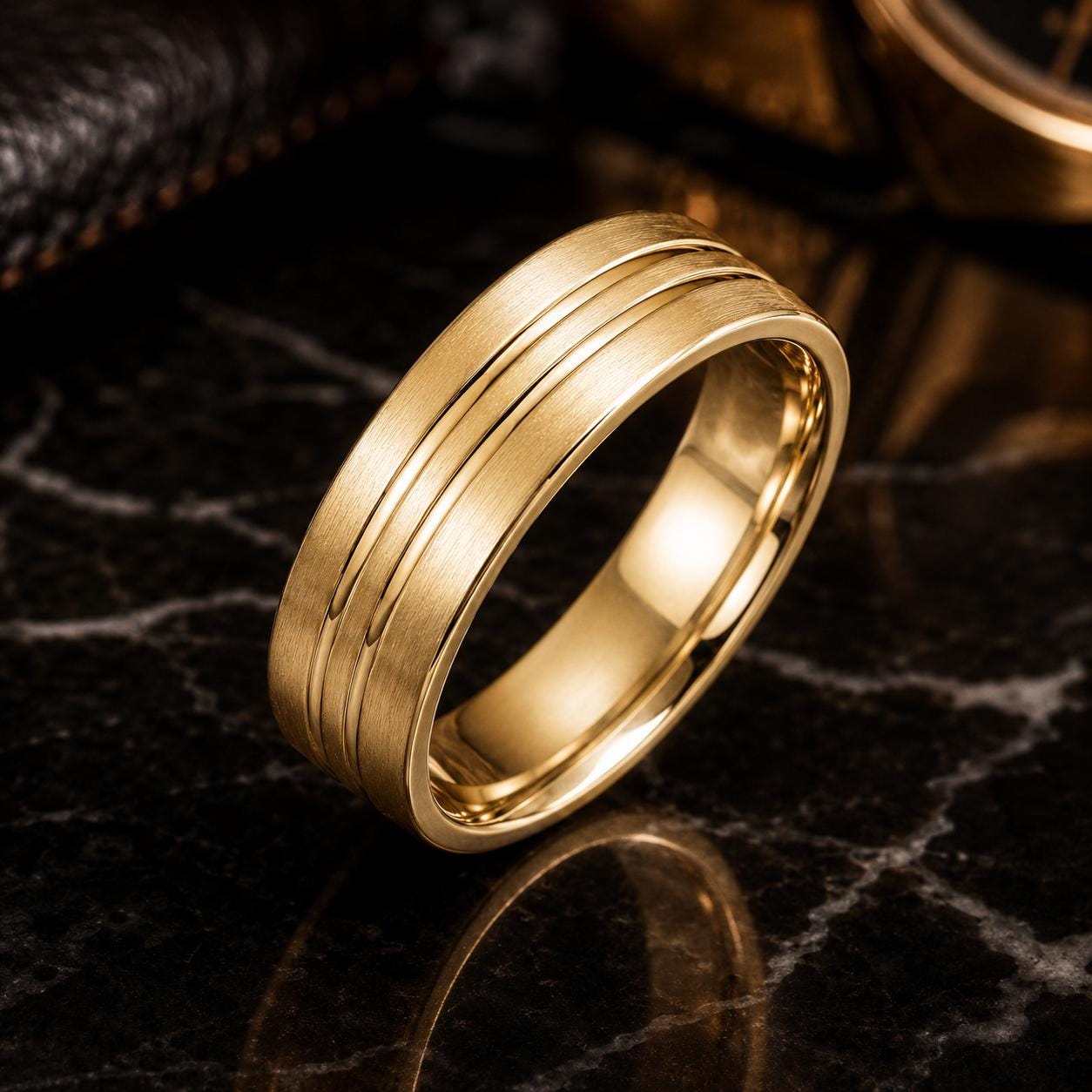 A gold ring with a simple, elegant design sits on a dark surface, reflecting the light.