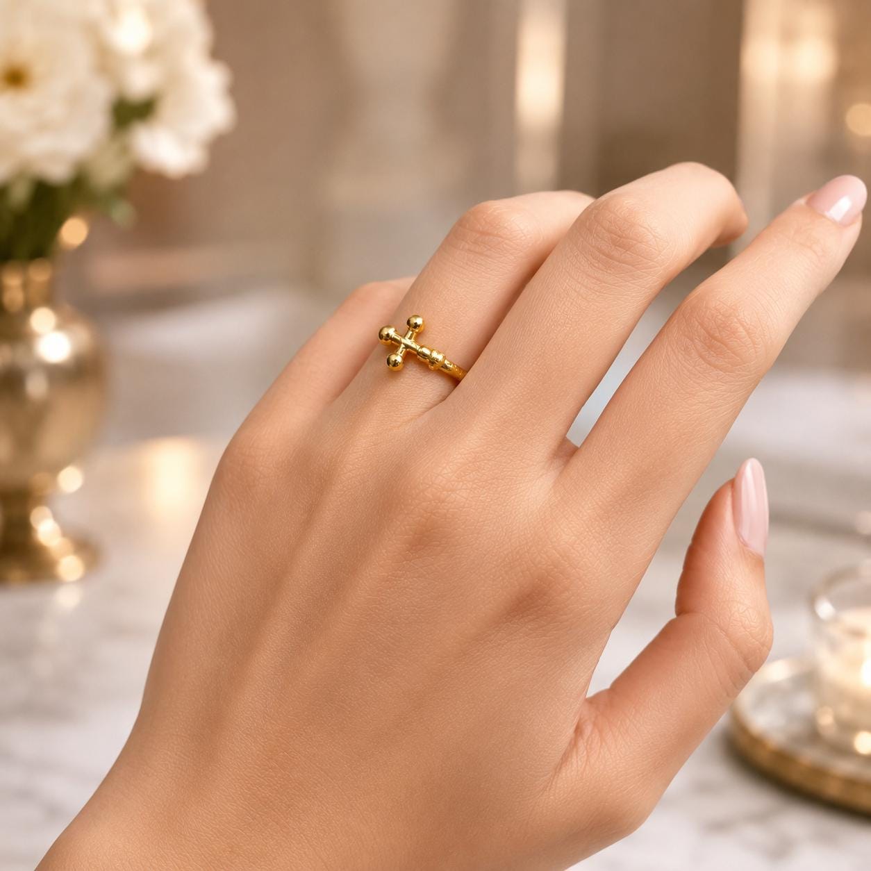 A close-up of a hand wearing a gold cross ring on the ring finger.