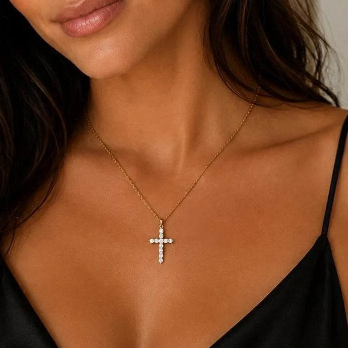 A woman with long, dark hair wearing a black dress and a cross necklace, smiling at the camera.