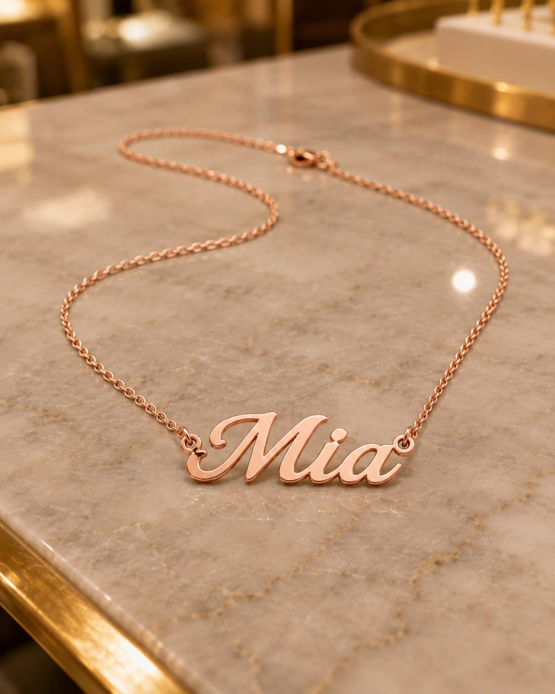 A necklace with the name "Mia" engraved on it, resting on a marble surface.