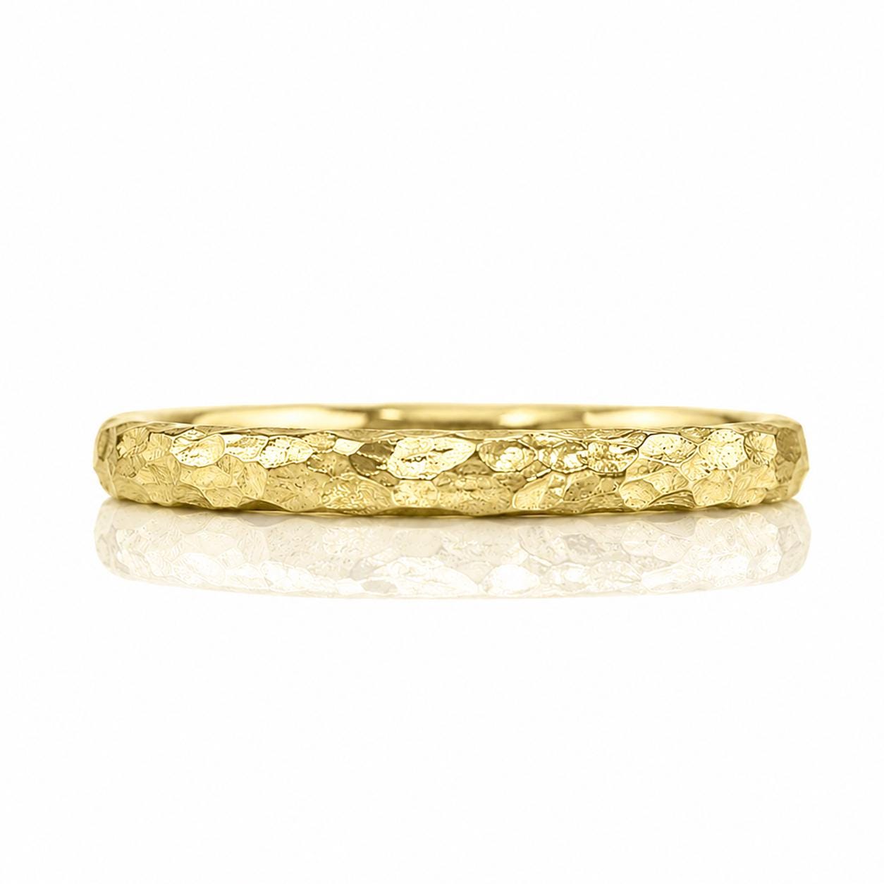 A gold ring with a textured surface, reflecting light and creating a shiny appearance.