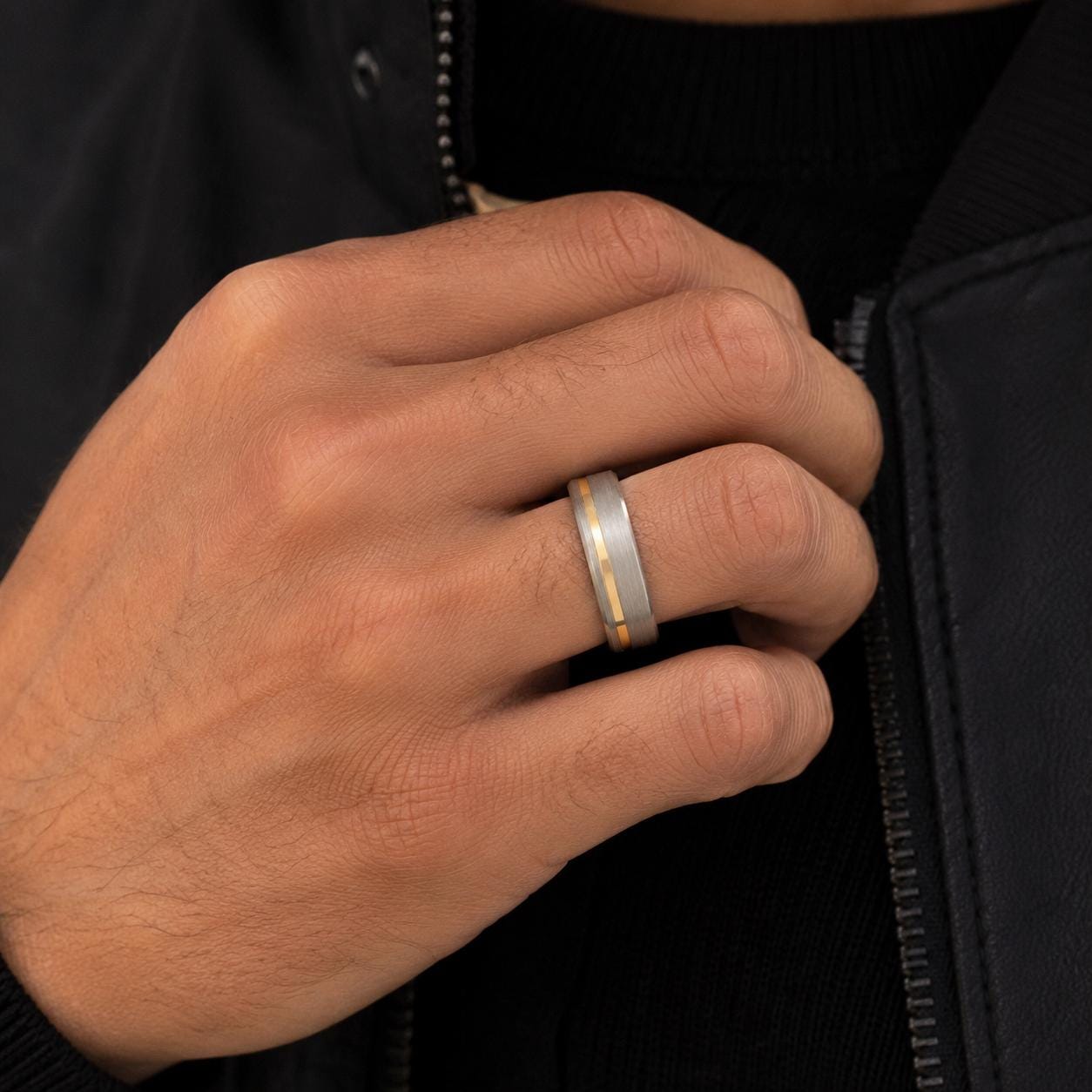 A close-up of a person's hand wearing a silver ring with a thin band.