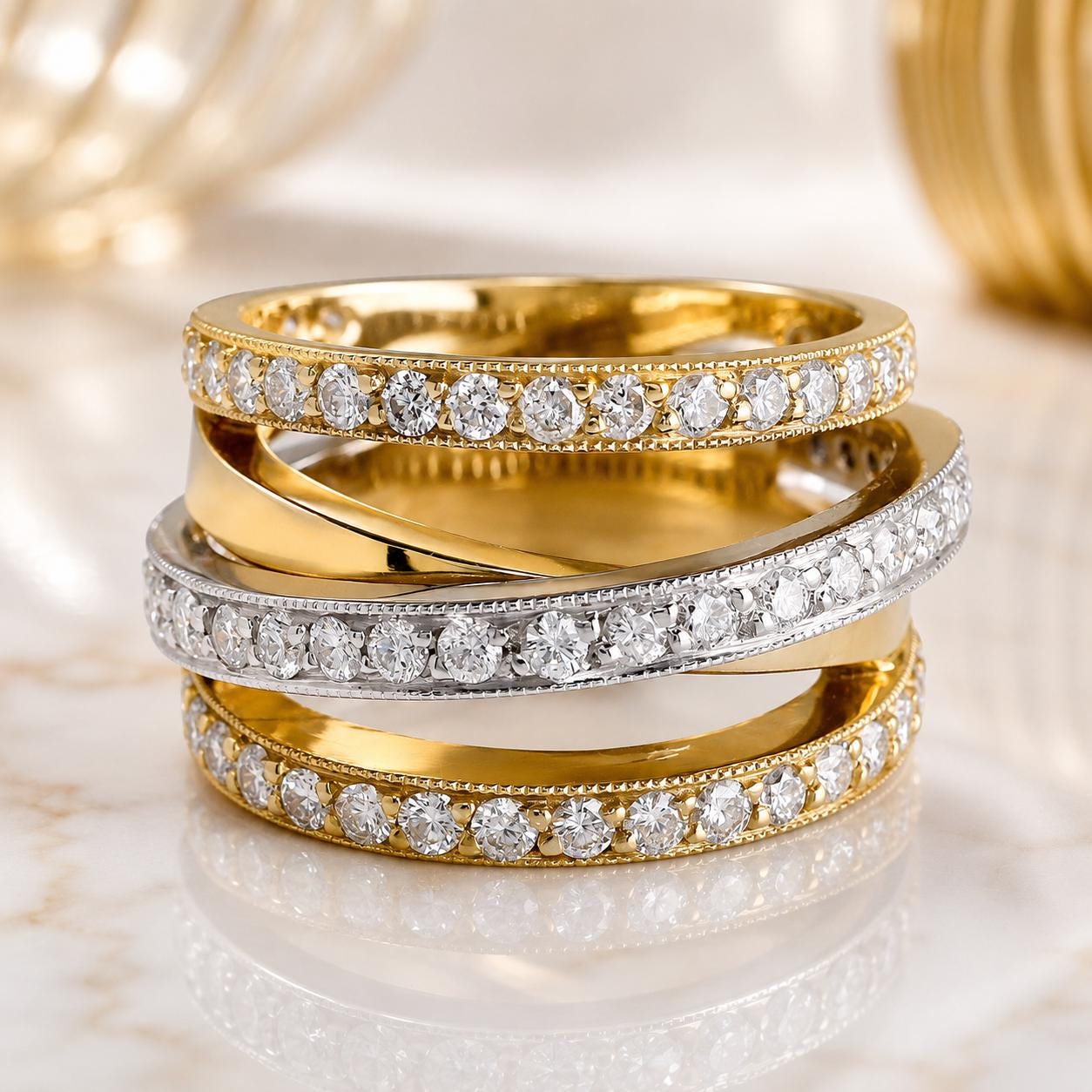 A stack of three gold and silver rings with diamond accents, placed on a marble surface.