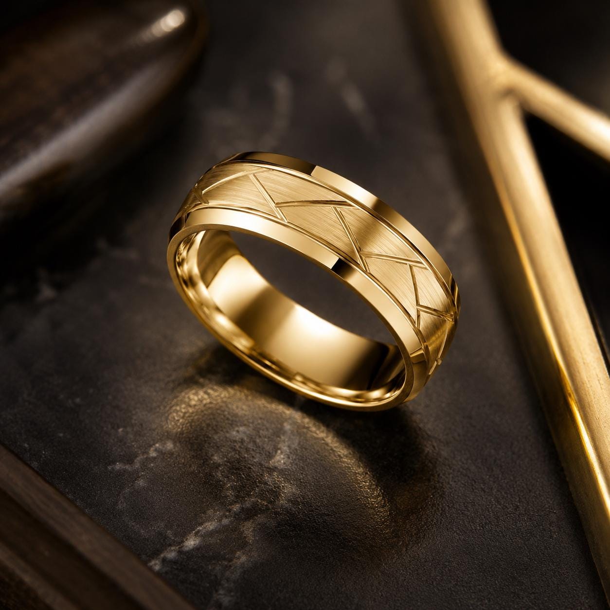 A gold ring with a geometric pattern sits on a dark surface, with a gold frame visible in the background.