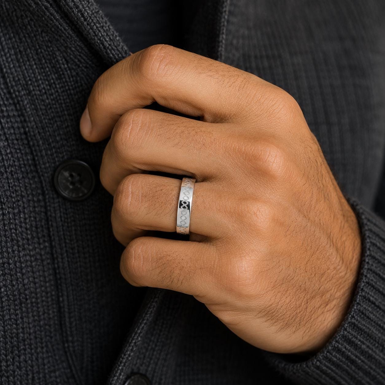 A close-up of a person's hand wearing a silver ring on the ring finger.