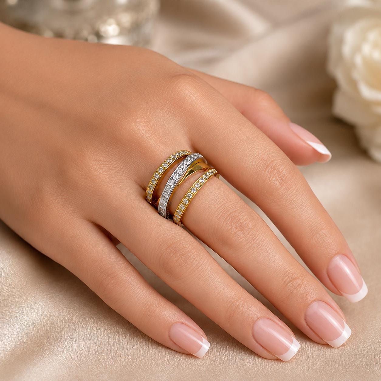 A close-up of a hand wearing a ring with multiple tiers of rings on the fingers.